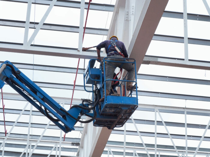 construction worker at construction site using lifting boom machinery
