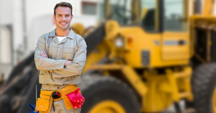 Worker standing with arms crossed against construction site in background