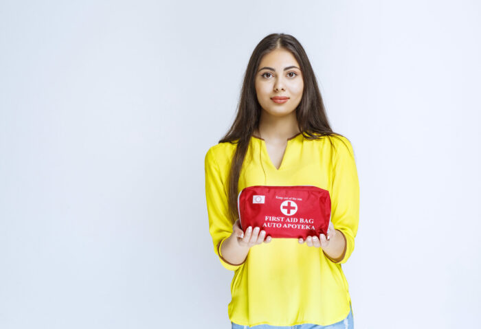 Girl holding and promoting a red first aid kit
