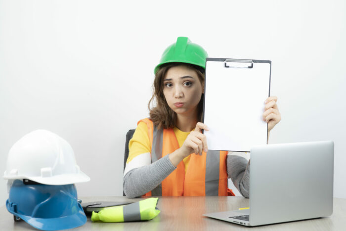Worker female in uniform sitting at the desk with laptop and clipboard